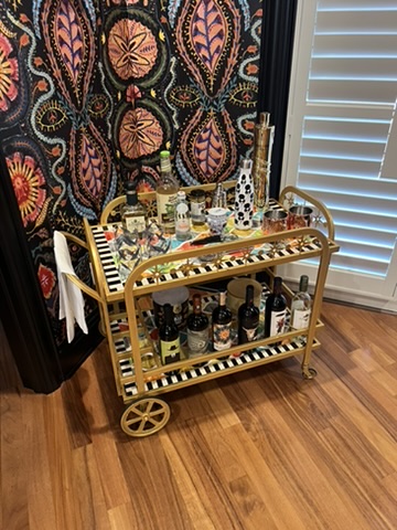 Styled bar cart detail layered against richly patterned wallcovering