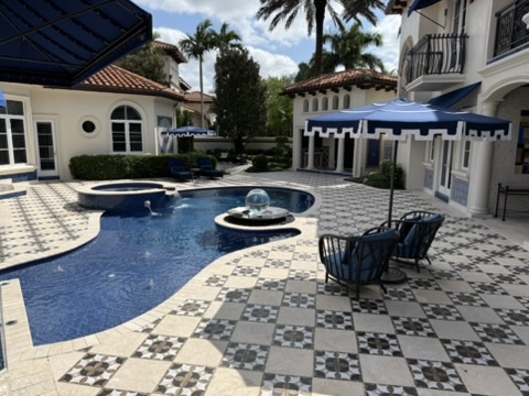 Covered entrance with columns, arched door, and patterned stone flooring