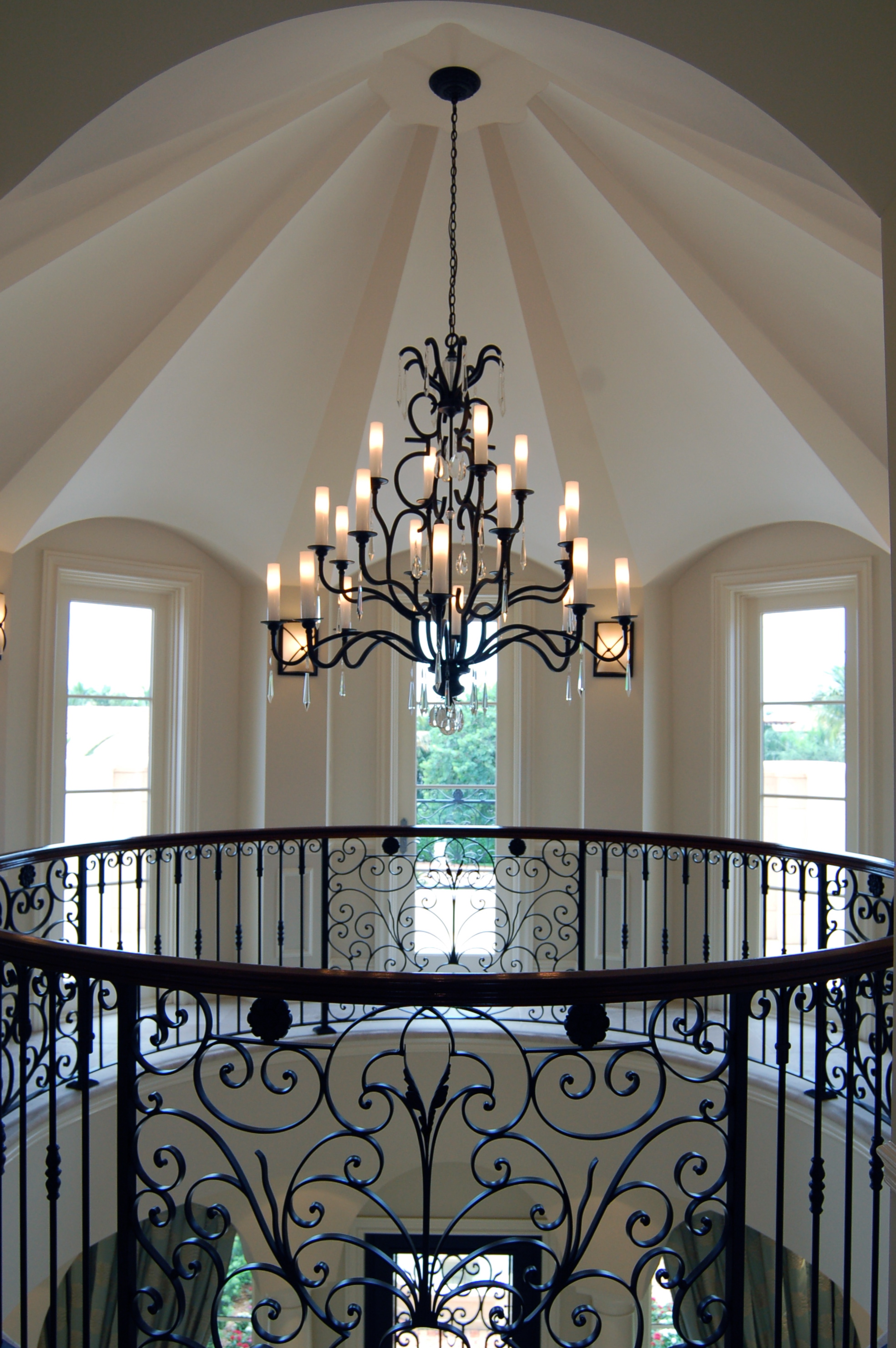 Double-height rotunda stair hall with wrought iron railing and chandelier