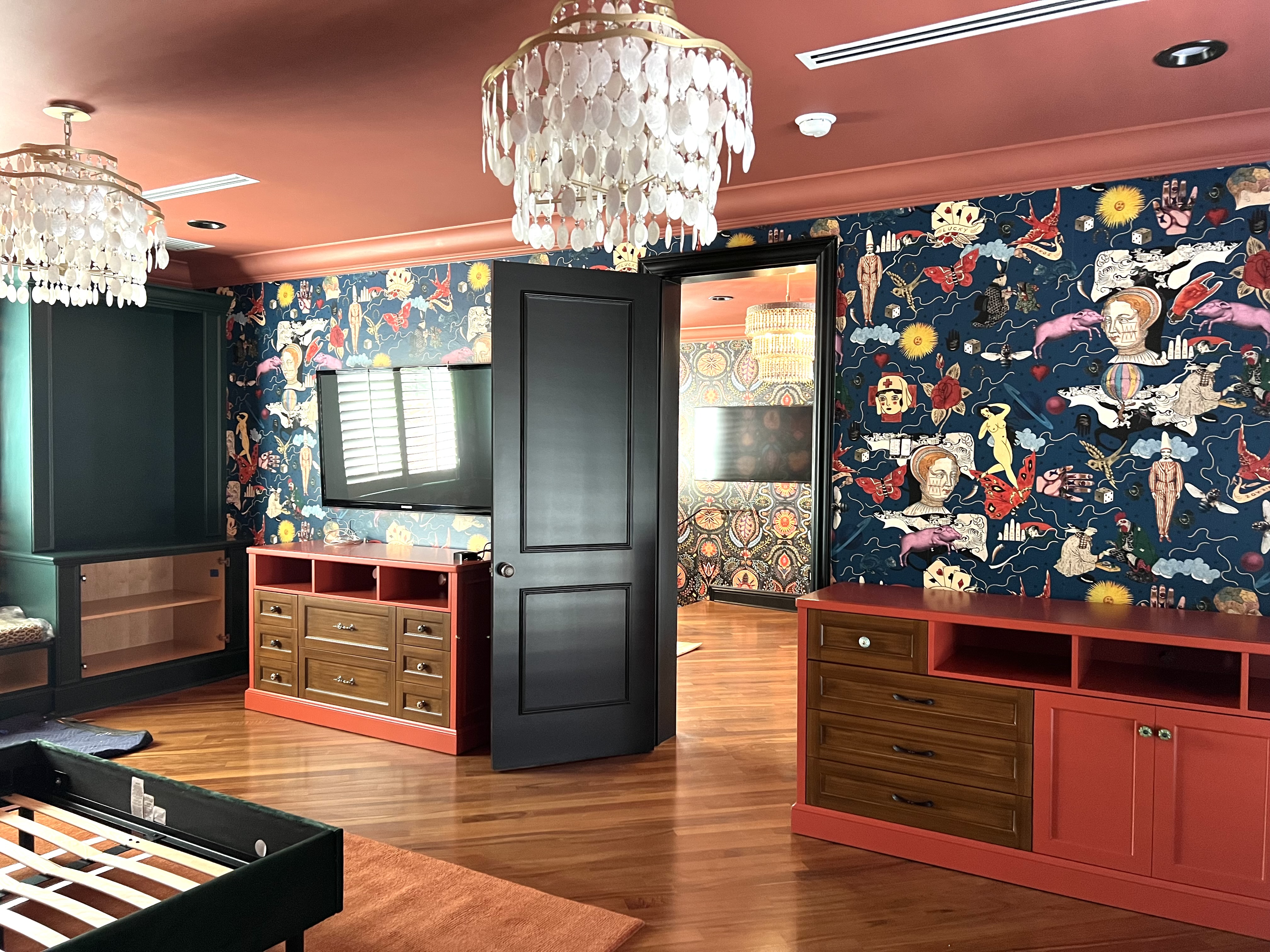 Bedroom view with custom cabinetry, wallpaper, and coral accents