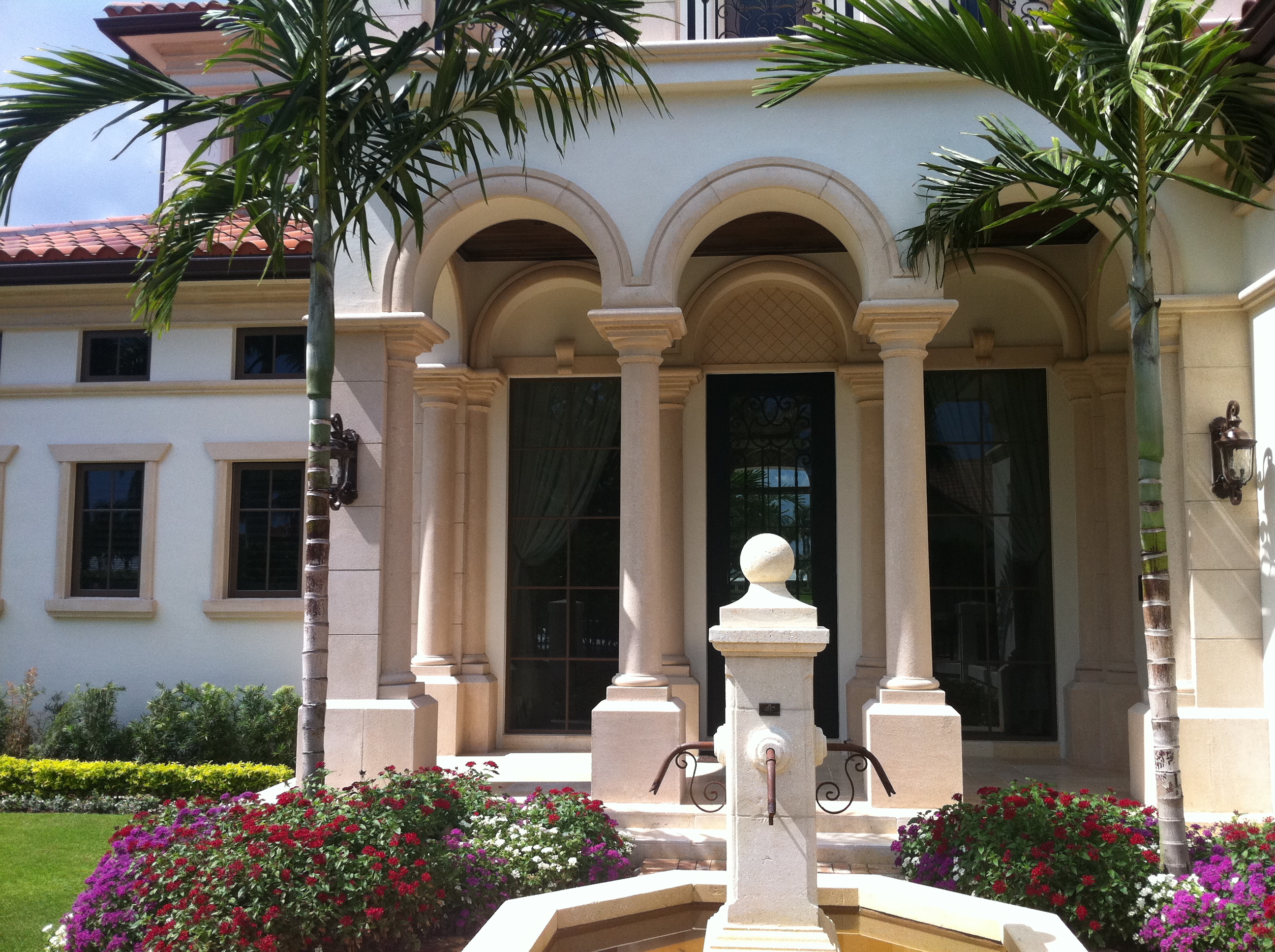 Estate exterior with arched entry and fountain