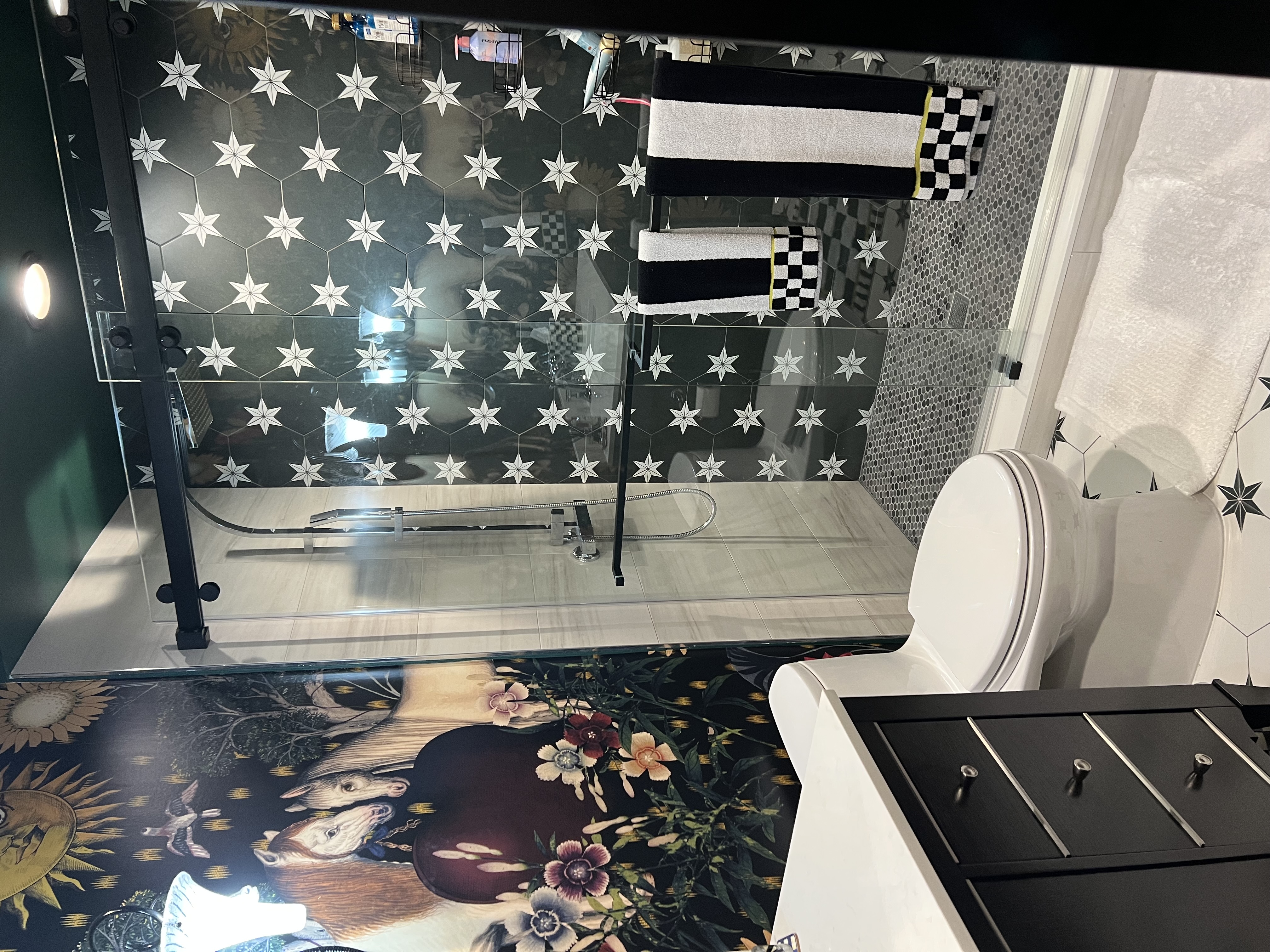 Maximalist powder room with equestrian mural wallpaper and graphic star-pattern shower tile