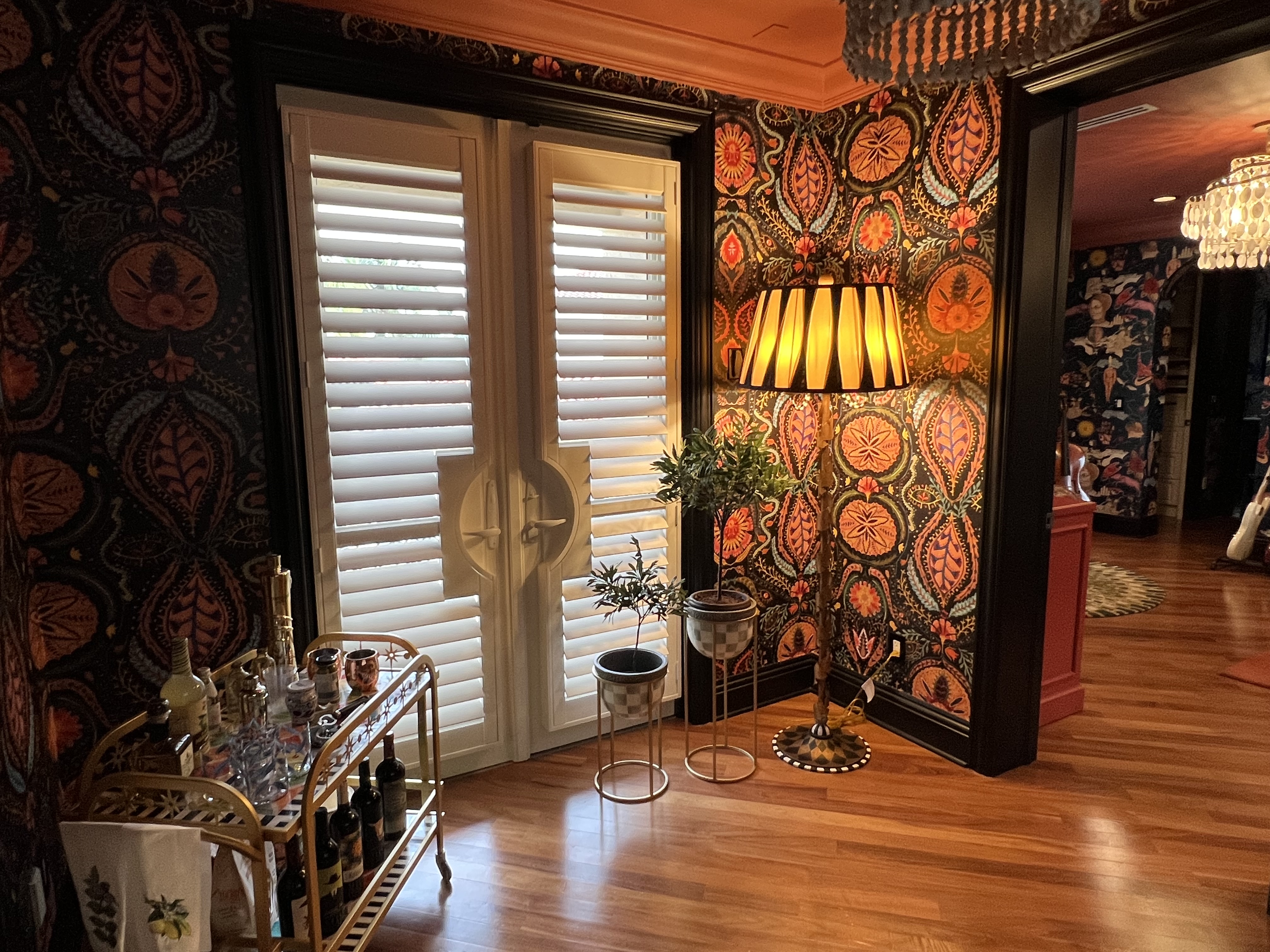 Hallway corner with richly patterned wallpaper, warm lamp, and shutters