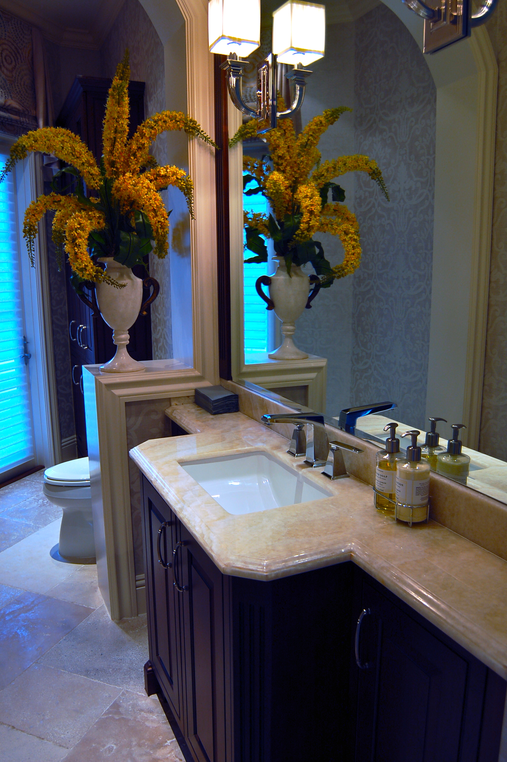 Bathroom vanity with stone top, dark cabinetry, and mirror detail