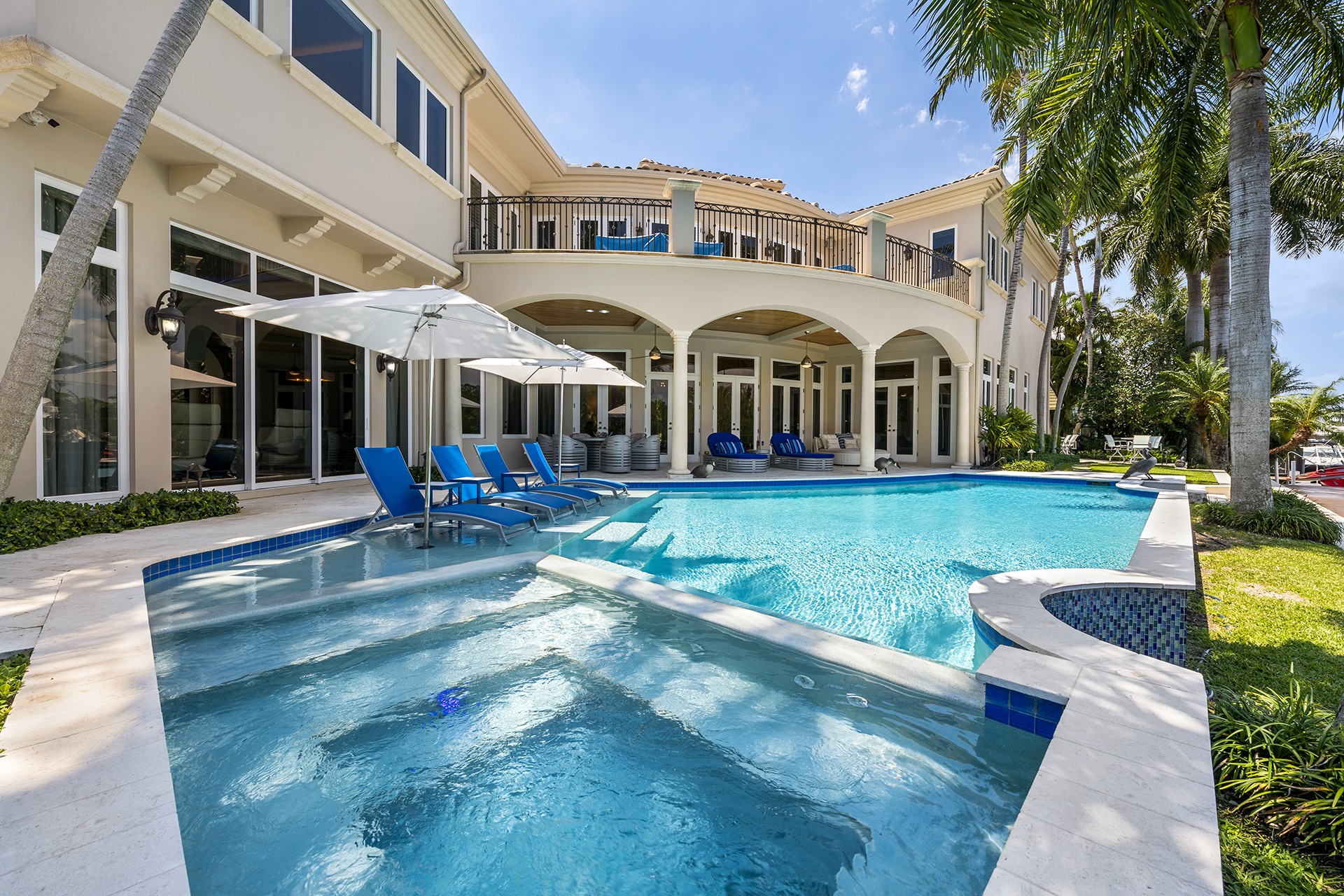 Intercoastal waterfront residence with pool, covered terrace, and upper balcony